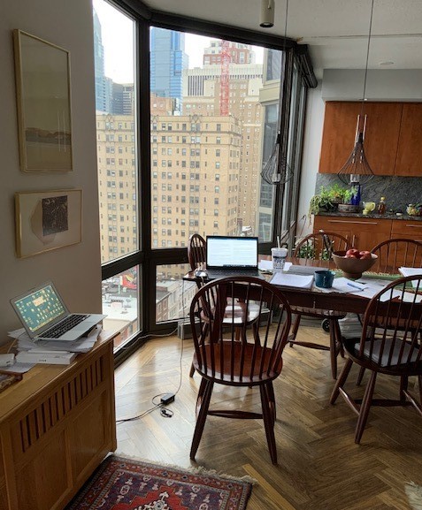 A laptop and papers on a dining room table with chairs